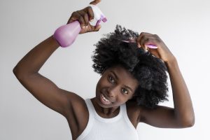 Black female moisturizing her natural hair